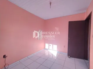 Interior de um cômodo com paredes cor de rosa e piso de cerâmica branca.