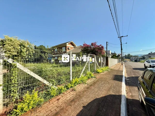 Vista externa de uma propriedade residencial com cerca e vegetação ao longo de uma rua.