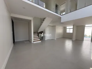 Espaço aberto de dois andares com piso claro e escadaria.