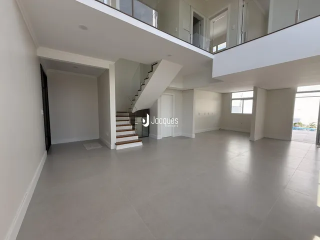 Espaço aberto de dois andares com piso claro e escadaria.
