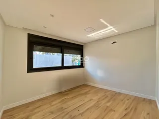 Ambiente interno de uma sala com piso de madeira clara e grande janela.