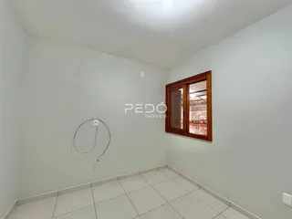Ambiente interno de uma sala com piso de cerâmica e janela de madeira.