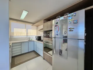 Vista interna de uma cozinha moderna com armários e eletrodomésticos de aço inoxidável.