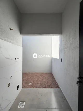 Hall de entrada com piso de concreto e armário branco na lateral.