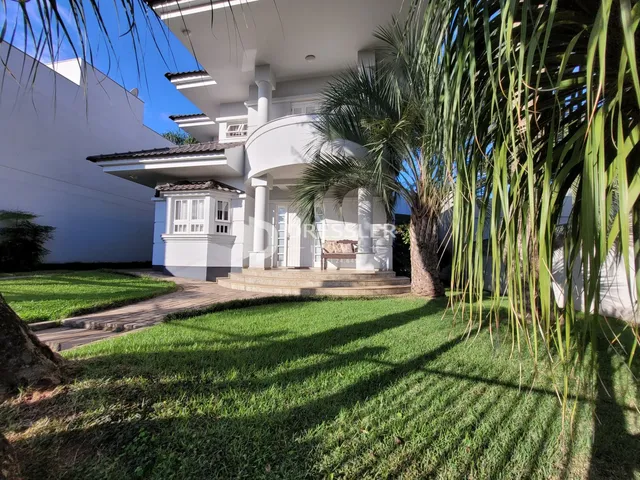 Fachada de uma casa branca com jardim verde em Lajeado, Brasil.