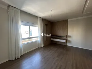 Ambiente interno com piso de madeira e grandes janelas em uma residência.