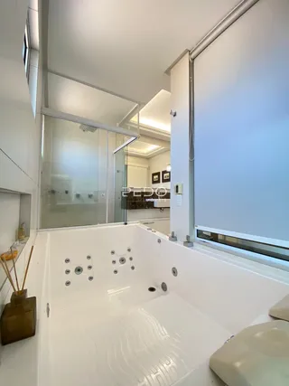Foto de um banheiro moderno com banheira e vidro em uma residência.