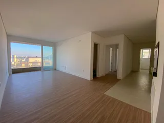 Sala de estar ampla com grande janela oferecendo vista para a paisagem urbana.