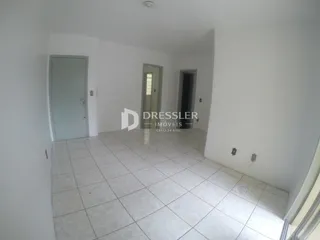 Vista de um corredor interno com piso de cerâmica clara e paredes brancas.