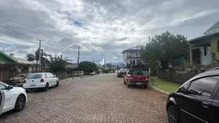 Vista da rua em Lajeado, Brasil, com casas e veículos estacionados.