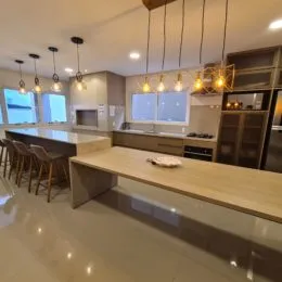 Cozinha moderna com bancadas claras e iluminação embutida em ambiente aberto.