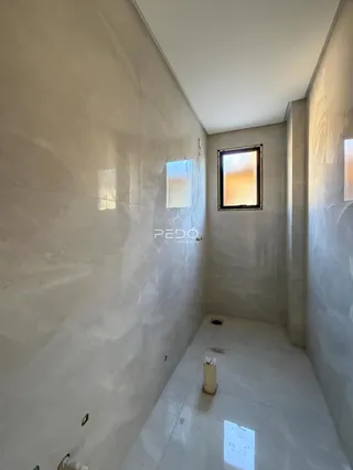 Vista de um corredor interno com paredes claras e piso de concreto.