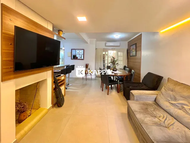 Sala de estar com sofá e televisão em um ambiente claro.