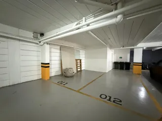 Foto de um espaço interno com paredes brancas e piso de concreto com marcações no chão.