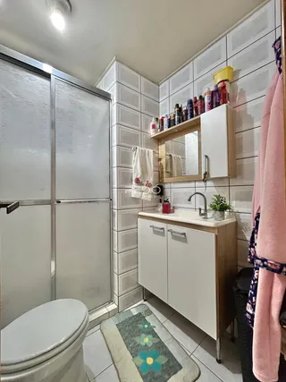 Foto de um banheiro com box de vidro e armário de apoio.