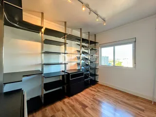 Ambiente interno com estantes metálicas escuras e piso de madeira clara.