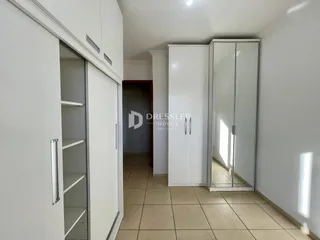 Vista de um corredor interno com armários embutidos e piso de cerâmica.