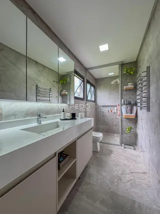 Imagem de um banheiro moderno com revestimento em mármore cinza e box de vidro.