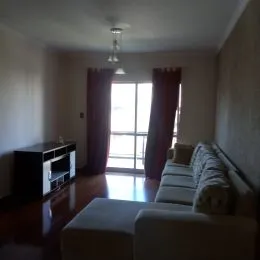 Sala de estar com piso de madeira e cortinas escuras.
