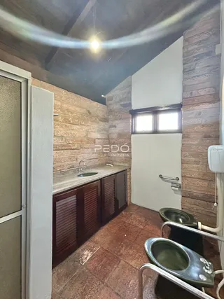 A cozinha apresenta armários de madeira e piso de terracota.