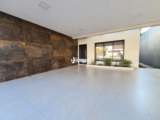 Foto de uma sala de estar ampla com piso claro e parede de destaque escura.