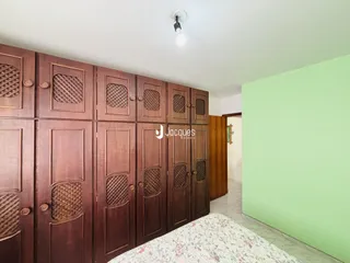 Quarto com armário de madeira escura e parede verde clara.