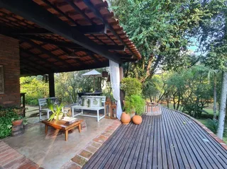 Vista de uma área externa de madeira com mobiliário no jardim.