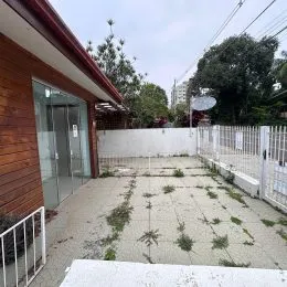 Foto de uma área externa com piso de concreto e vegetação em um imóvel.