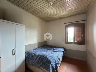 Quarto com cama e armário branco em ambiente com teto de madeira.