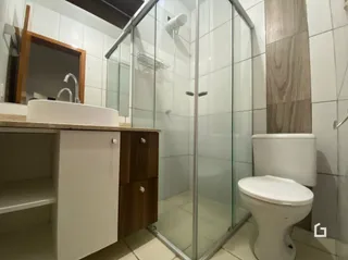 Foto de um banheiro com box de vidro e louças sanitárias.