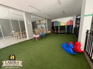espaço interno com piso de grama sintética e brinquedos infláveis