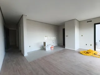 Vista interna de um ambiente com paredes brancas e piso de concreto.