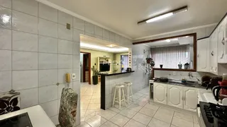 Interior de uma sala de estar com revestimento de azulejos claros e acesso à cozinha.