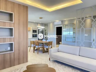 Sala de estar moderna com sofá branco e mesa de jantar em um apartamento em Lajeado.