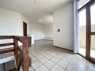 Hall de entrada com piso de cerâmica e corrimão de madeira.