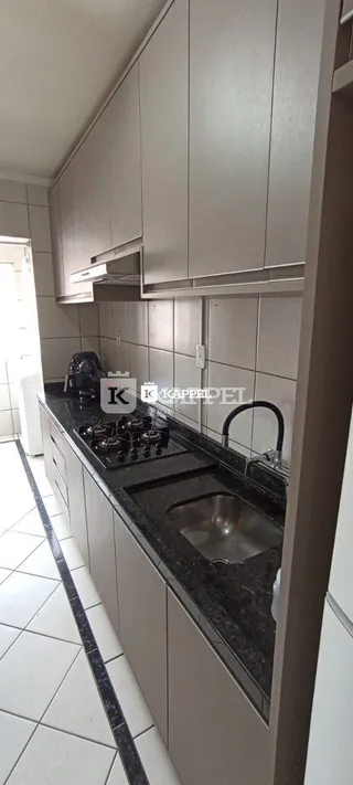 Vista de armários superiores e inferiores de cozinha com bancada escura e pia.