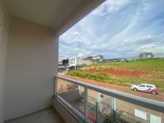 Vista externa de uma propriedade com terreno em terra vermelha e vegetação ao fundo.