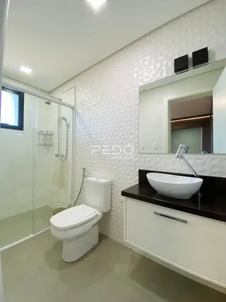 Foto de um banheiro moderno com box de vidro e vaso sanitário branco.