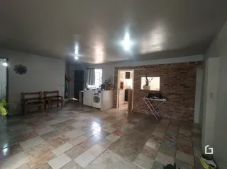 Vista interna de uma sala com piso de cerâmica e parede de tijolos aparentes.