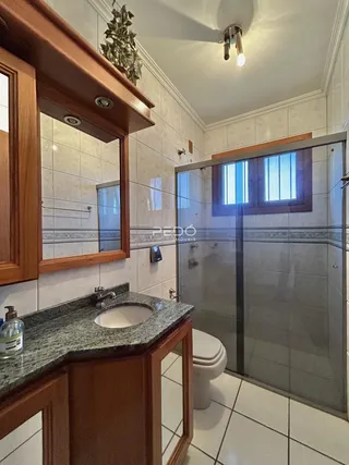 Banheiro com box de vidro e revestimento cerâmico nas paredes.