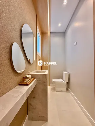 Banheiro moderno com bancada de mármore e espelho decorativo.