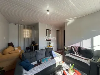 Sala de estar com sofá e cortinas em um imóvel no Brasil.