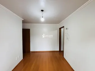 Vista interna de um ambiente com piso de madeira e paredes brancas.