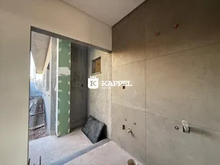 Hall de entrada com paredes de concreto aparente em uma construção em andamento.