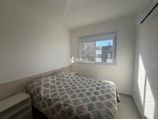 Quarto com cama e janela em ambiente claro.
