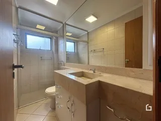 Banheiro com box de vidro e bancada de mármore.
