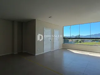 Ambiente interno de uma sala com piso de cerâmica e grandes janelas.
