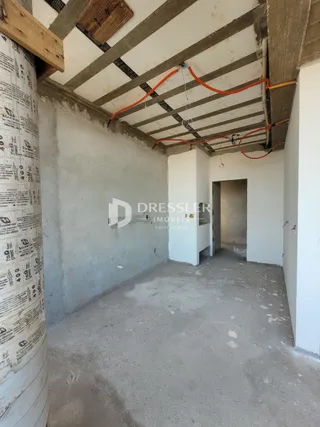 Espaço interno com estrutura de concreto aparente e paredes brancas.