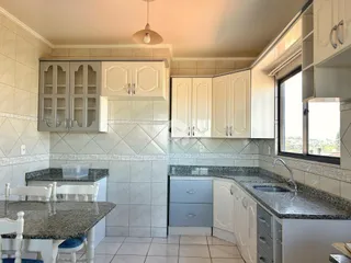 Foto de uma cozinha com armários brancos e bancadas de granito.