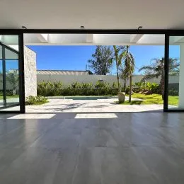 Vista externa de um pátio com vegetação ao fundo.